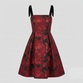 A sleeveless V-neck dress with a red and black floral jacquard pattern, featuring black ribbon shoulder straps, shown against a solid light gray background.