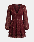 A long-sleeve mini dress in deep burgundy with a gold geometric pattern, featuring a gathered waist and sheer puff sleeves, shown against a light gray background.