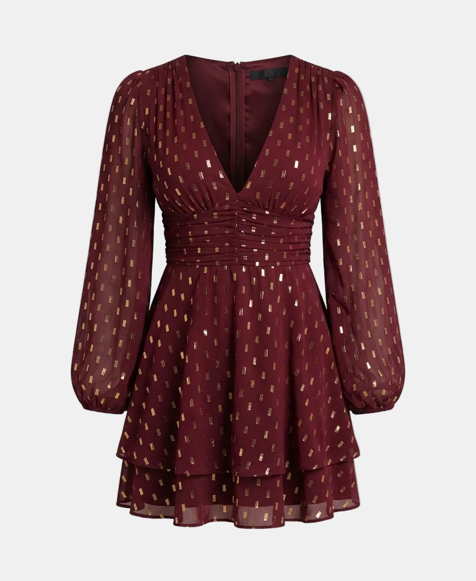 A long-sleeve mini dress in deep burgundy with a gold geometric pattern, featuring a gathered waist and sheer puff sleeves, shown against a light gray background.