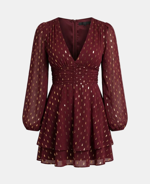 A long-sleeve mini dress in deep burgundy with a gold geometric pattern, featuring a gathered waist and sheer puff sleeves, shown against a light gray background.