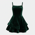 A green velvet mini dress with thin spaghetti straps, a structured sweetheart bodice, and a flared tiered skirt, shown against a light gray background.