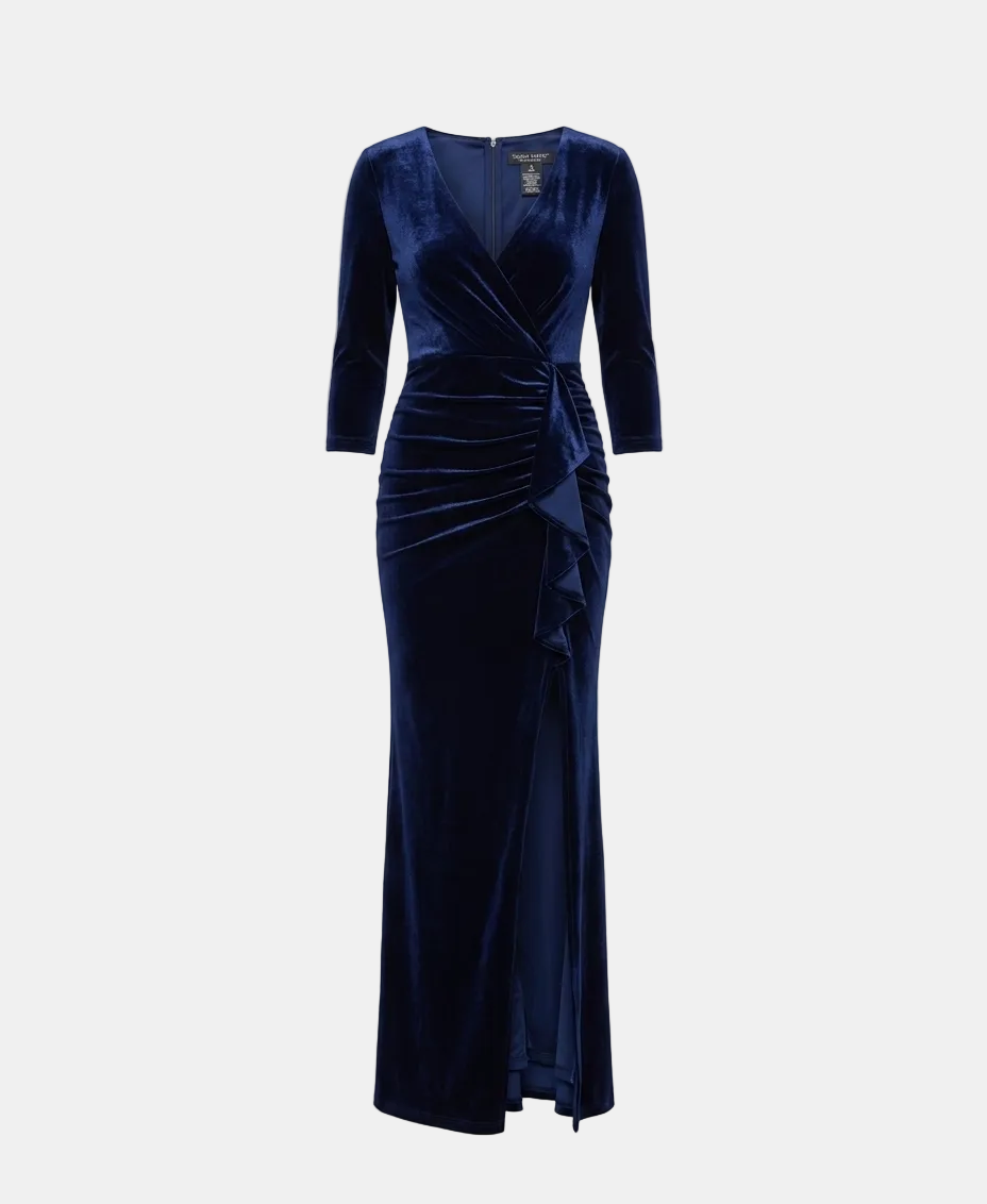 A floor-length navy blue velvet gown with three-quarter sleeves, a wrap-style V-neck bodice, and gathered draping details, shown on a light gray studio background.
