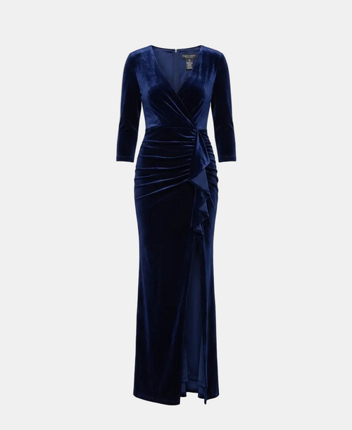 A floor-length navy blue velvet gown with three-quarter sleeves, a wrap-style V-neck bodice, and gathered draping details, shown on a light gray studio background.