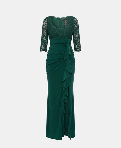 A floor-length emerald green gown with a lace bodice, three-quarter sleeves, and a ruched draped skirt with ruffle detailing, shown on a neutral light gray background.